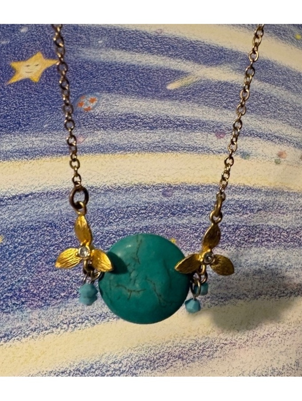 brass-toned necklace with circle of turquoise and small gold tone leaves